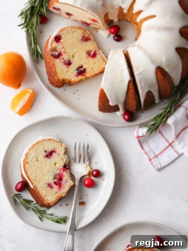 Πορτοκαλένιο Κέικ με Κράνμπερι 9 Φέτα κέικ bundt σε πιάτο με κομμάτια που λείπουν