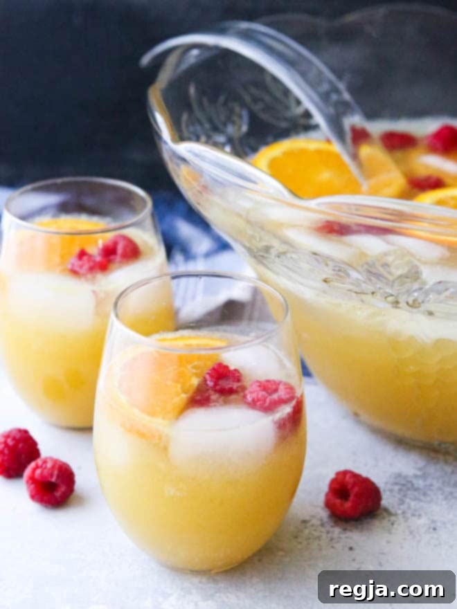 Κοντινό πλάνο Mimosa Punch με φέτες πορτοκαλιού και σμέουρα