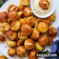 Κουλουράκια πρέτζελ σε πιάτο με μπολ σάλτσας μέλι-μουστάρδα