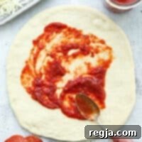 Απλώνεται σάλτσα πίτσας σε ζύμη