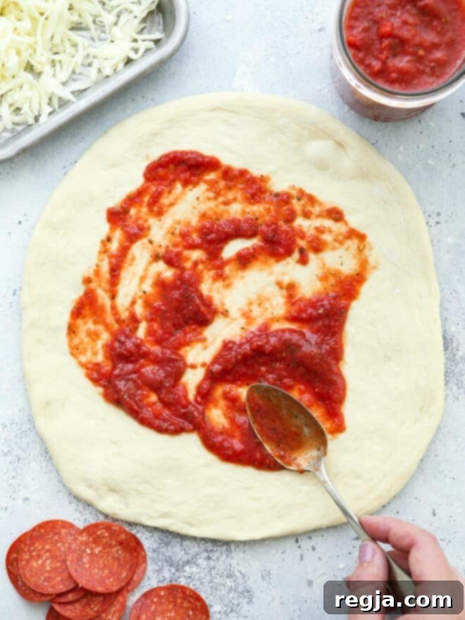 Απλώνεται σάλτσα πίτσας σε ζύμη